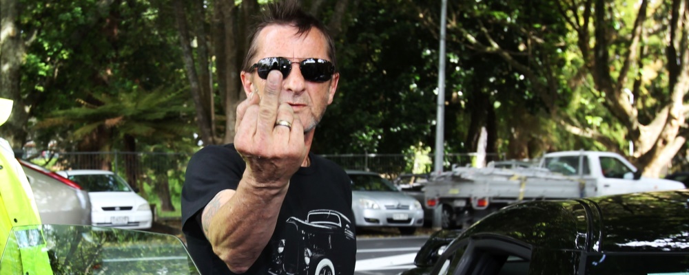 TAURANGA, NEW ZEALAND - NOVEMBER 26:  AC/DC drummer Phil Rudd gestures to members of the media after leaving Tauranga District Court after appearing in court after being charged with threatening to kill and possession of meth and marijuana at Tauranga District Court on November 26, 2014 in Tauranga, New Zealand.  Phil Rudd was ACDC's drummer from 1975 to 1983.  (Photo by Joel Ford/Getty Images)