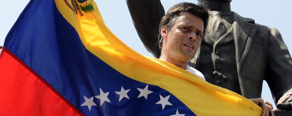 Leopoldo Lopez, an ardent opponent of Venezuela's socialist government facing an arrest warrant after President Nicolas Maduro ordered his arrest on charges of homicide and inciting violence, stands at the monument of Cuba's most important independence-era hero, Jose Marti, as he demonstrates with a national flag in Caracas before turning himself in to authorities, on February 18, 2014. Fugitive Venezuelan opposition leader Lopez, blamed by Maduro for violent clashes that left three people dead last week, appeared at an anti-government rally in eastern Caracas and quickly surrendered to the National Guard after delivering a brief speech. AFP PHOTO / LEO RAMIREZ